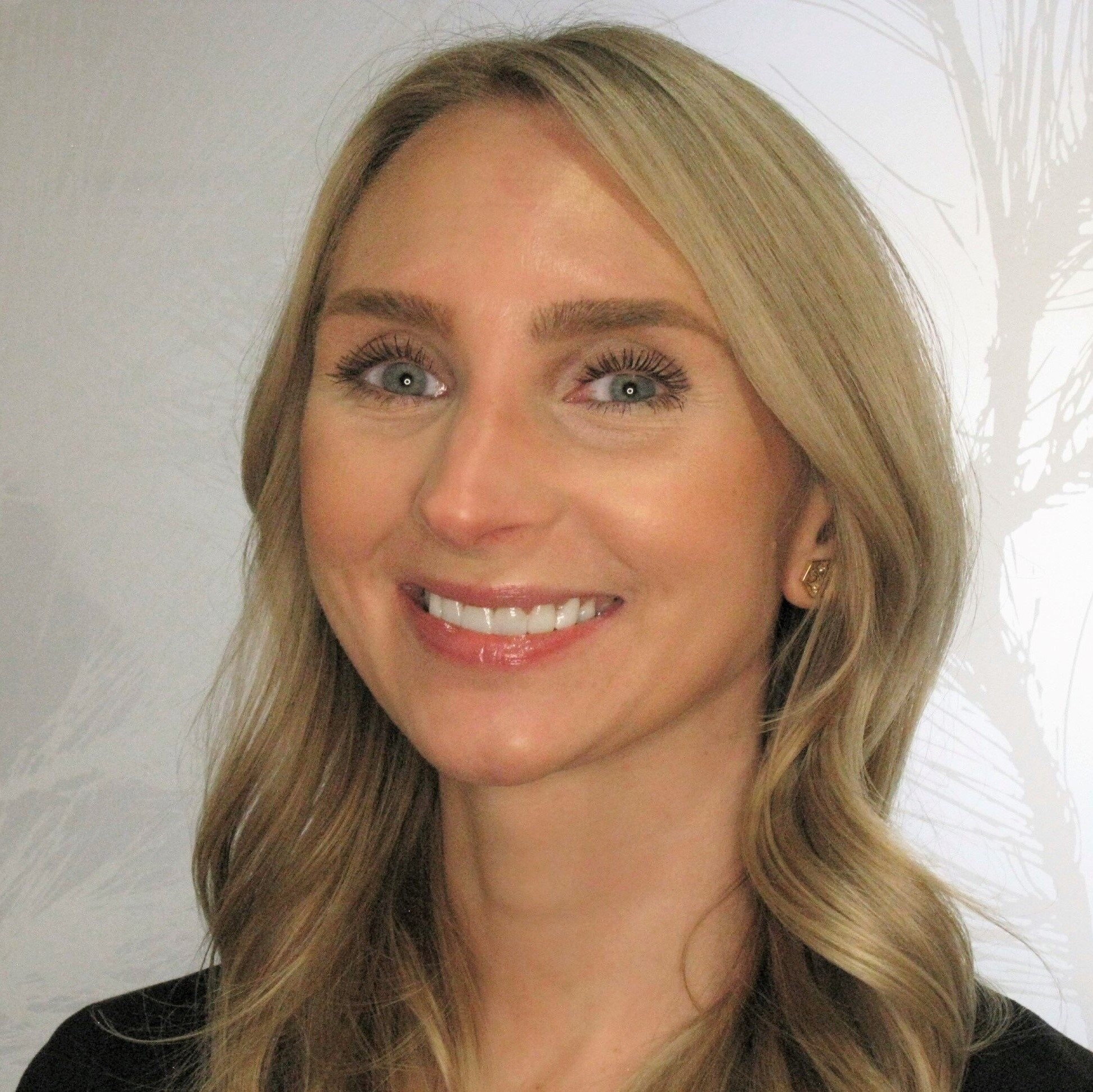 Professional headshot of smiling woman with blonde wavy hair against white background for dental practice.
