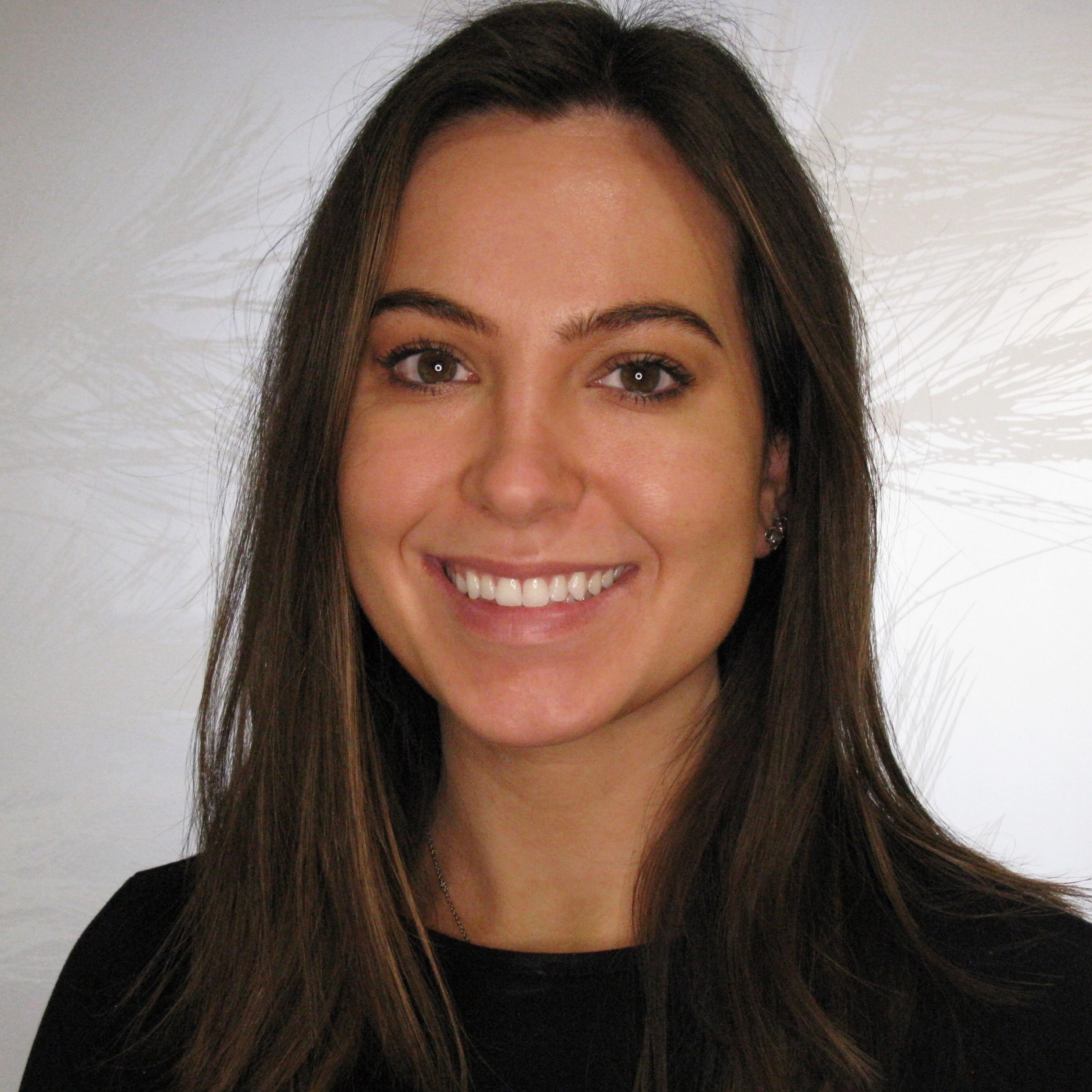 Professional headshot of a smiling woman with long dark hair against a white background.
